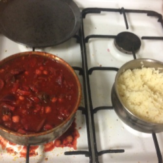 Two pots on a stove - one full of curry, the other has rice