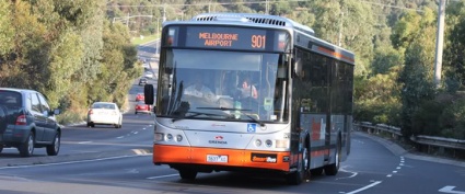 A black, grey & orange Smartbus is driving on a road. Its destination is Melbourne Airport 901