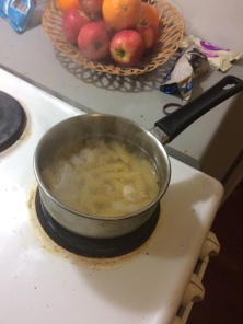 spiral pasta simmers in a silver pot with a black plastic handle on the stove
