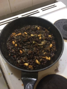 in the black frypan, the onion, mushrooms and peanuts are mixing with the black beans