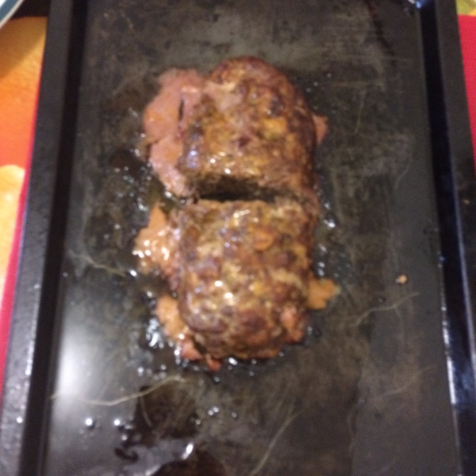 Cooked meatloaf on a black baking tray viewed from above